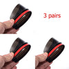 Three pairs of black carbon fiber car side mirror rain and sun visors being held by a hand.