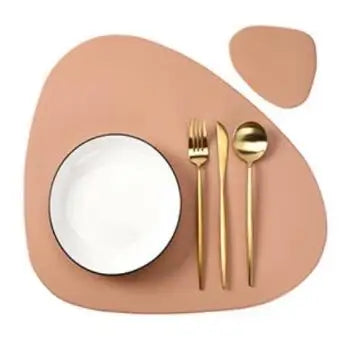 A beige placemat features a white bowl and a gold fork and spoon set.