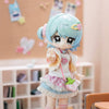 A light blue articulated BJD collectible figurine with pink hair and a white outfit is displayed in a shelf setting.