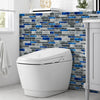 A white toilet is shown in front of a dark blue and gray mosaic tile backsplash.