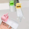 A hand holds a pink rabbit-themed anti-splash faucet extender for kids, next to two yellow and green faucet extenders.
