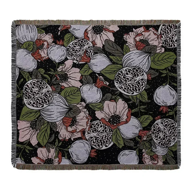 A dark floral pattern woven throw blanket featuring roses and leaves in muted pinks, greens, and whites.