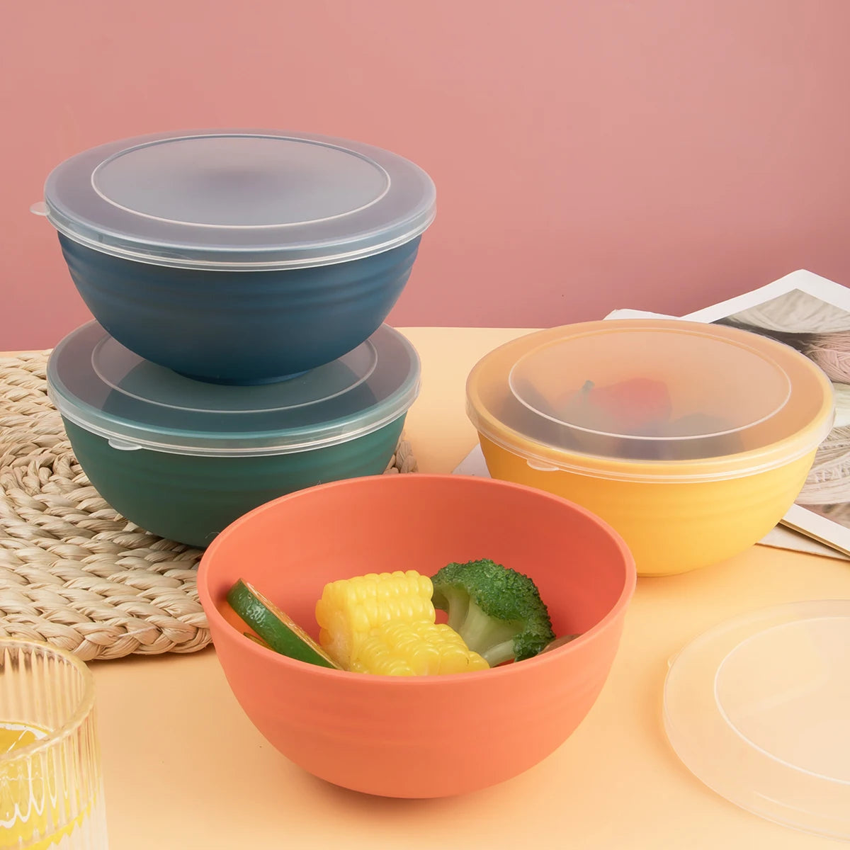 A set of three terracotta and yellow storage bowls with matching lids displayed on a light orange surface.