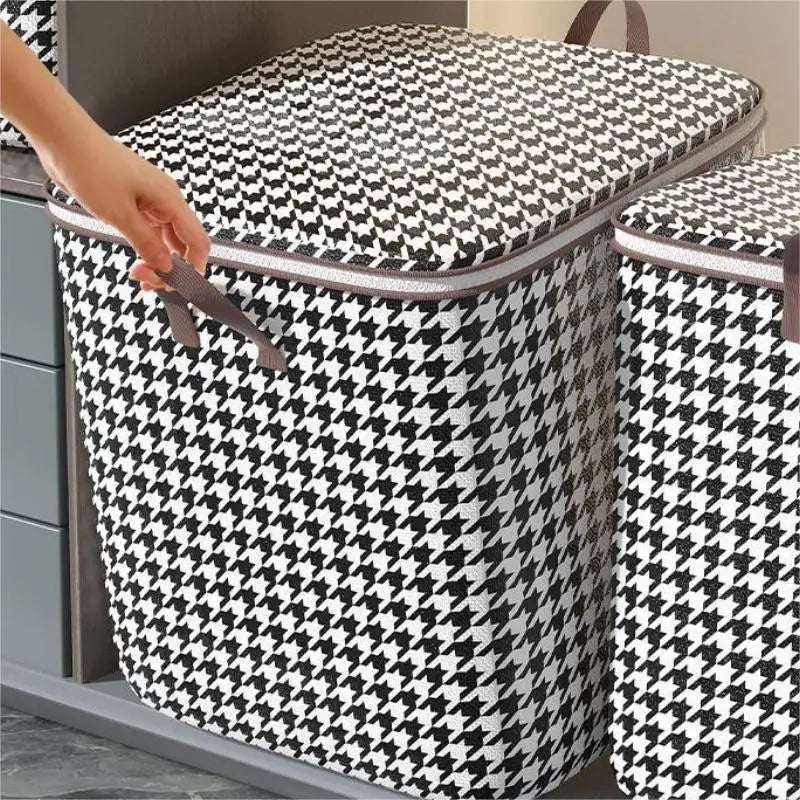 A hand is opening a patterned fabric storage bag for clothes or quilts.