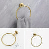 A set of four gold-toned stainless steel bathroom accessories including a toilet paper holder, towel ring, and hooks.