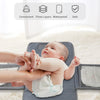 A baby is being changed on a gray portable diaper changing pad with a waterproof cover and storage bag.
