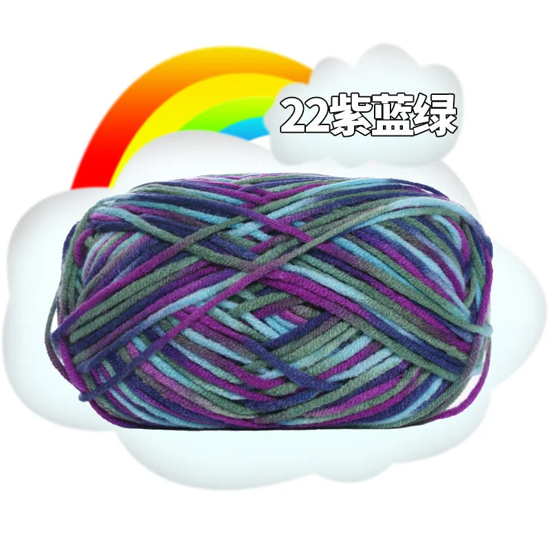 A ball of purple and green milk cotton blend yarn with a rainbow graphic above it.
