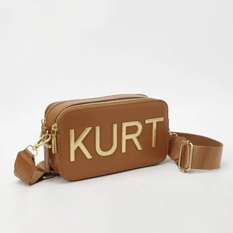 Braune Ledertasche mit goldfarbenem KURT-Eingravur und tanem Riemen.