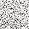 A close-up view of small white and black acrylic letter beads scattered on a white surface.