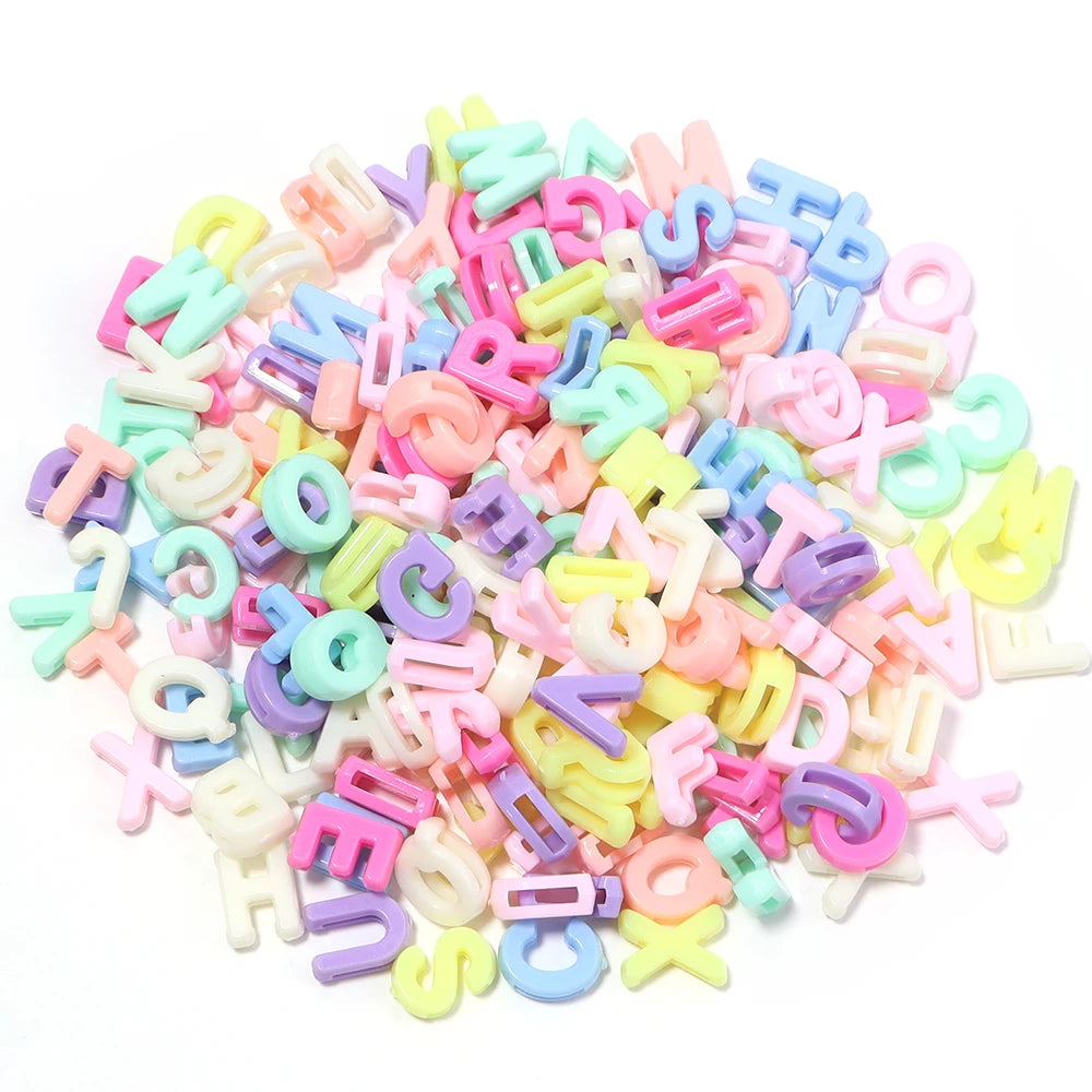 Haufen gemischter Buchstaben-Spacer-Perlen in Pastellfarben wie rosa, blau, gelb und weiß.