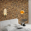 A bedroom featuring a leopard print wallpaper behind a white bed and bedside lamp.