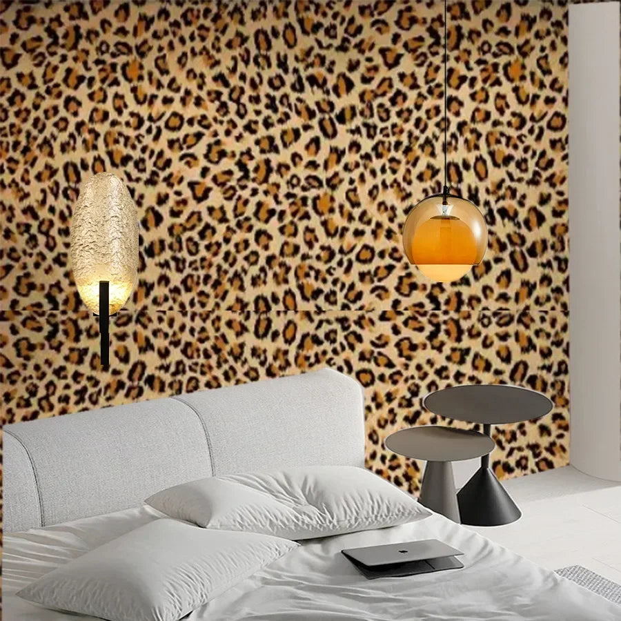 A bedroom featuring a leopard print wallpaper behind a white bed and bedside lamp.