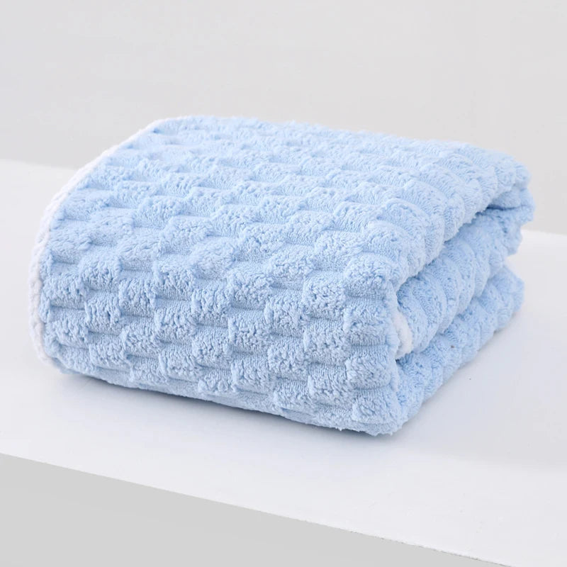A folded light blue plush bath towel with a textured, quilted pattern.