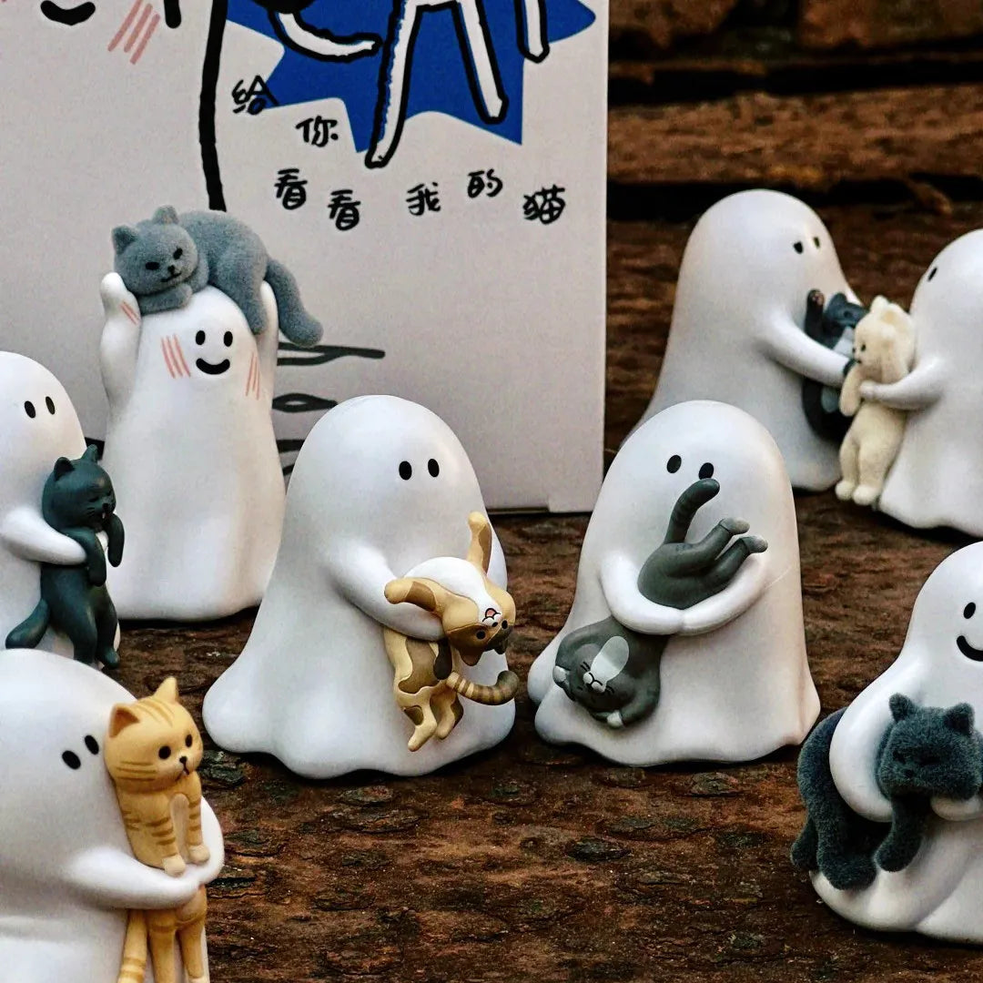 A collection of white ghost-like figurines, some holding cats and other small animals, displayed in front of a box with Chine