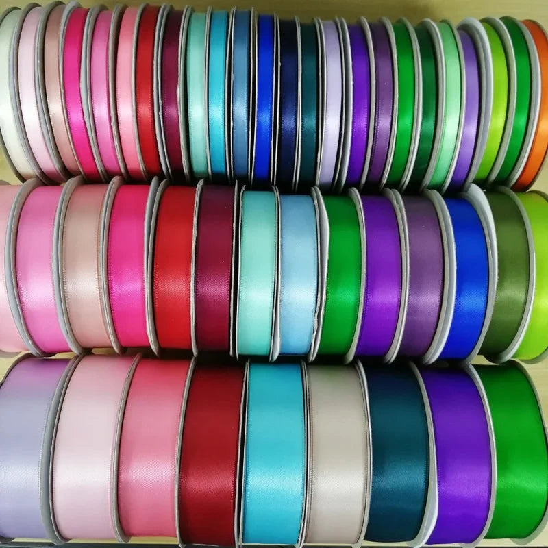A stack of double face satin ribbon in various solid colors, including pink, teal, purple, and green.