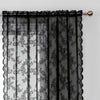 Black lace curtain panel with floral pattern and sheer fabric hanging from a rod.
