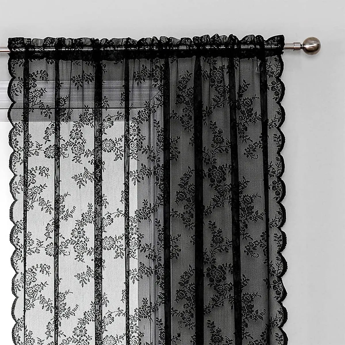 Black lace curtain panel with floral pattern and sheer fabric hanging from a rod.