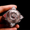 A hand holds a premium metal spinner dice cube with intricate patterns against a black background.