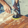 A person is using an electric sander with foam sanding pads on a wooden surface.