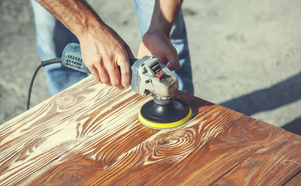 A person is using an electric sander with foam sanding pads on a wooden surface.