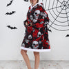 Eine Frau modelliert einen kuscheligen, oversized Fleece-Hoodie mit Totenkopf-Aufdruck vor einer weißen Wand mit schwarzen Fl