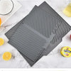 A gray silicone dish drying mat with textured ridges is shown next to citrus fruits and a jar of Spread.