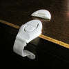 A white adhesive baby proofing latch for drawers, cupboards, and fridges, shown on a dark wooden surface.