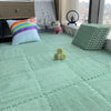 A bright teal floor with interlocking soft plush tiles, a stuffed animal, and decorative items.