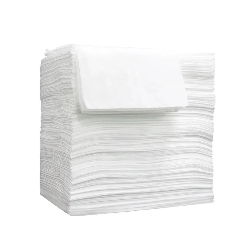 A stack of white disposable bed sheets for salons, spas, and travel.