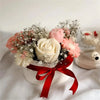 A bouquet of pink and cream floral silicone molds with dried flowers and greenery tied with a red ribbon.