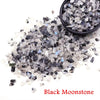 A pile of black moonstone crystal chips and tumbled stones for healing and decoration.