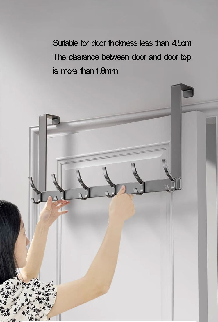 A close-up of a silver over-the-door organizer rack with eight hooks being installed on a white door frame.