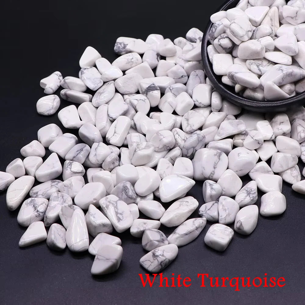 Pile of white turquoise tumbled crystal stone chips scattered on a dark surface.
