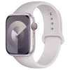 A silver silicone sport band for an Apple Watch shown on a white wrist.