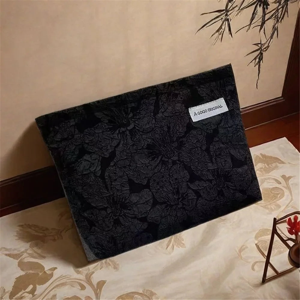 A dark gray canvas charger storage pouch with a floral pattern resting on a light-colored surface.