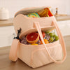 A light pink insulated reusable lunch bag filled with ice and various food items.