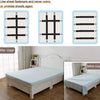 A set of four black elastic corner straps used to fasten bed sheets, shown alongside a white wooden bed frame.