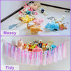 A comparison showing messy and tidy arrangements of plush toys stored in a bohemian handwoven net with tassels.