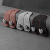 Three leather headrest hooks in brown, gray, and black with heart-shaped grips