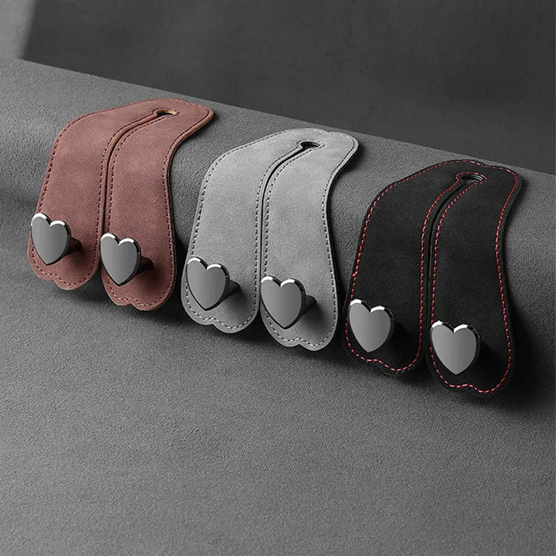 Three leather headrest hooks in brown, gray, and black with heart-shaped grips