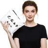 A woman holds a white toiletry bag with the word CRAP written on it.