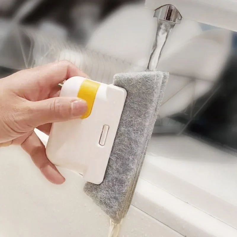 A hand is using a multi-purpose crevice cleaning brush to clean window tracks or tight spaces.