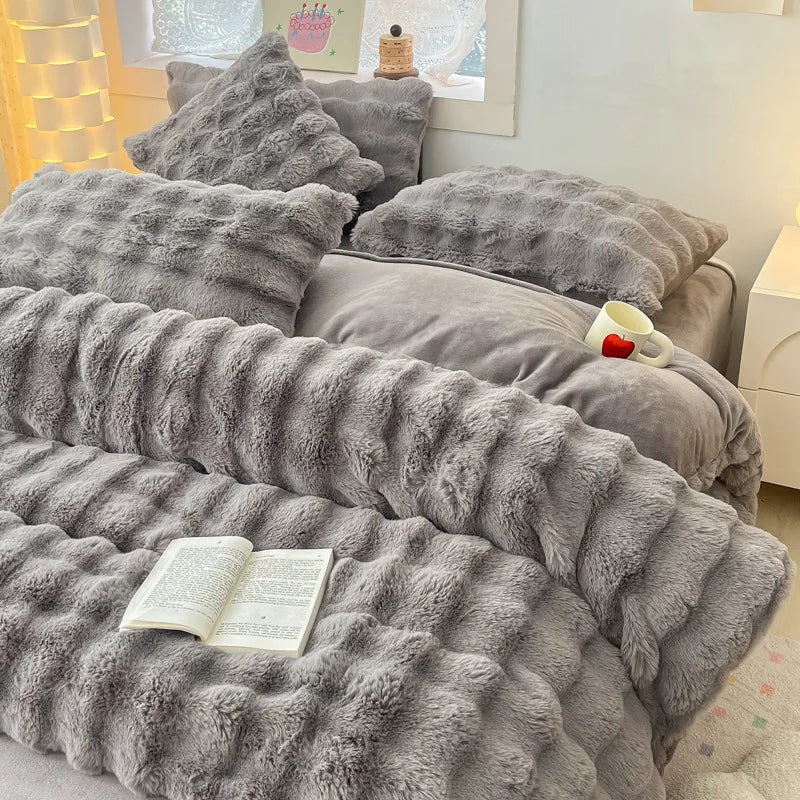 A gray ultra-soft plush bedding set featuring pillows and a textured blanket on a bed.