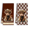 Two Highland cow plaid kitchen towels featuring a brown calf with a floral crown.