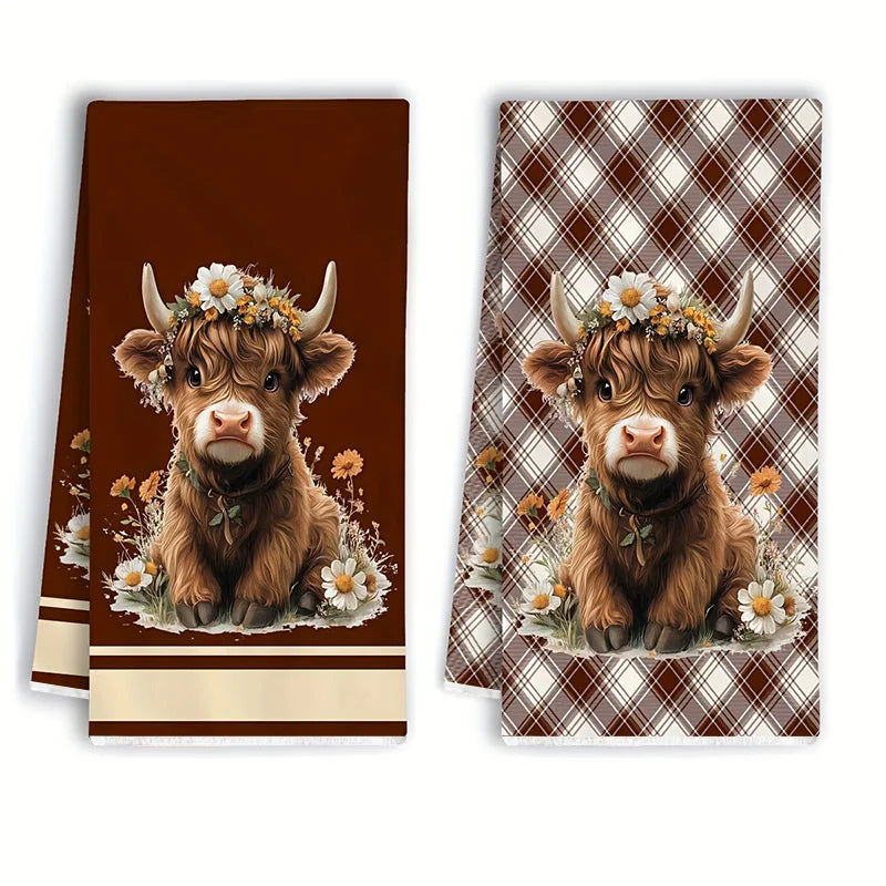 Two Highland cow plaid kitchen towels featuring a brown calf with a floral crown.