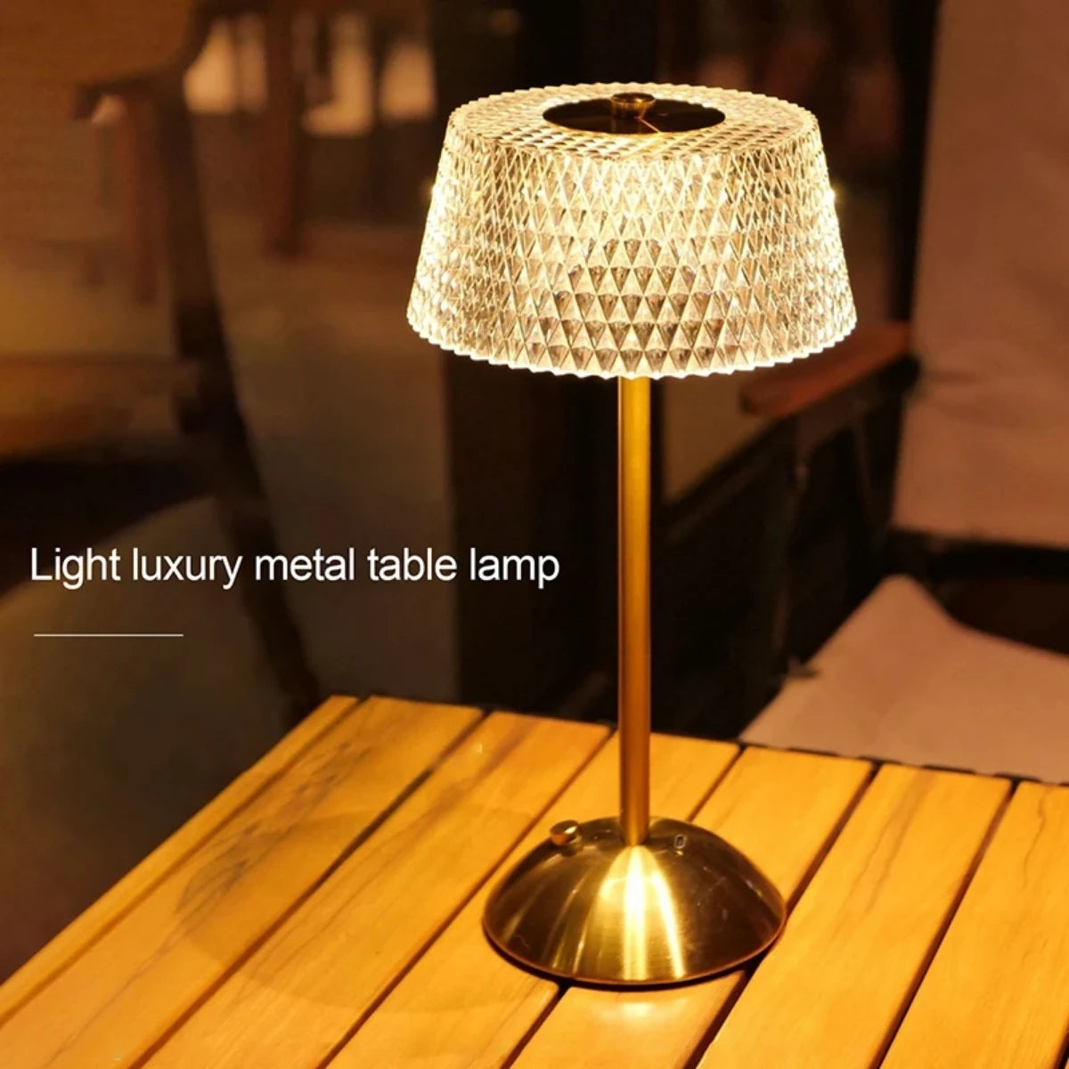 A gold-toned metal table lamp with a textured shade sits on a wooden surface.