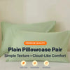 A pair of plain light green pillowcases showing simple texture and cloud-like comfort features