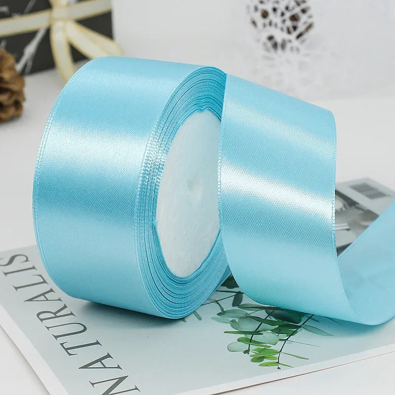 A roll of light blue satin ribbon used for gift wrapping or DIY crafts.