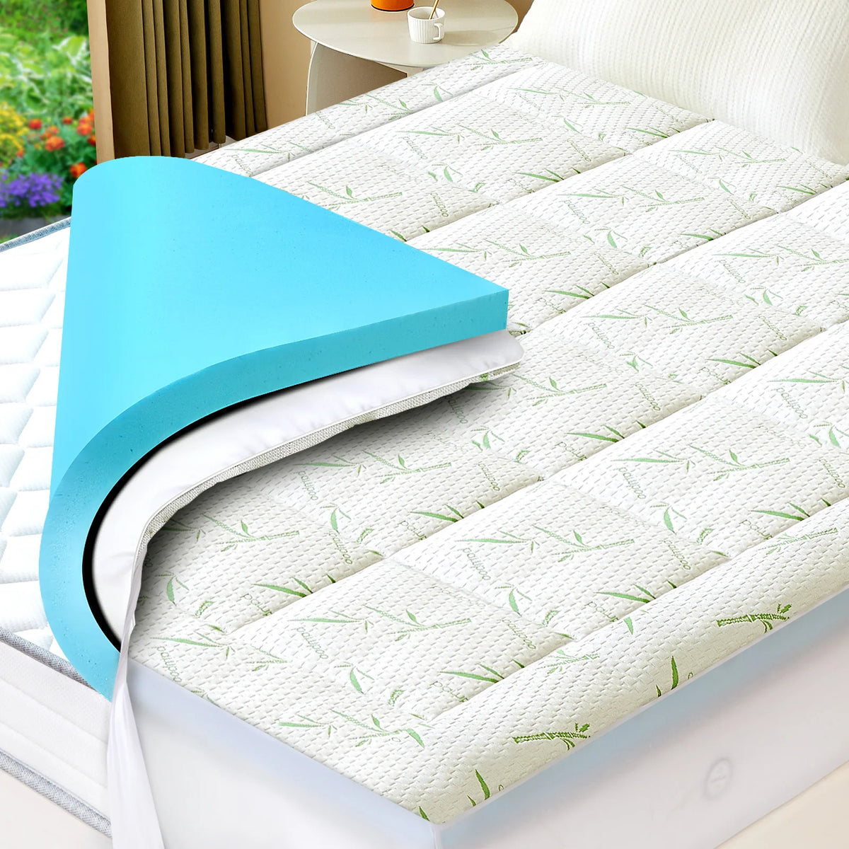 Helles blaues Memory-Schaum-Topper mit weiß-grünem Blattmuster auf einem Bett.