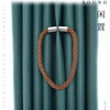 A close-up shot of a brown rope magnetic curtain tieback with a silver buckle clasp against a teal fabric background.